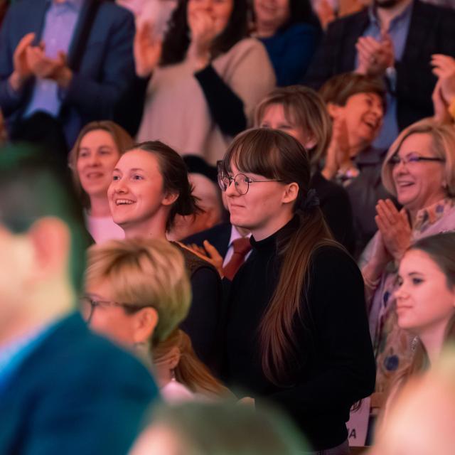 Skupiona i poruszona publiczność reaguje na koncert, nagradzając występ brawami.